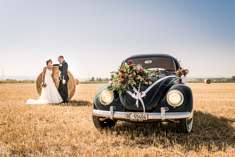 Brautpaar mit VW Kaefer auf abgemaetem Kornfeld